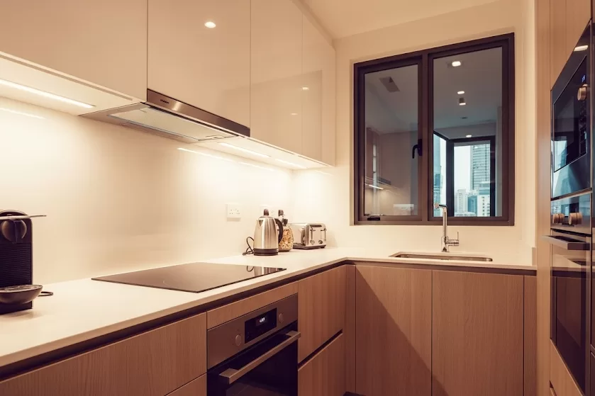 Small condo kitchen in Singapore with under-cabinet task lighting and warm tones.